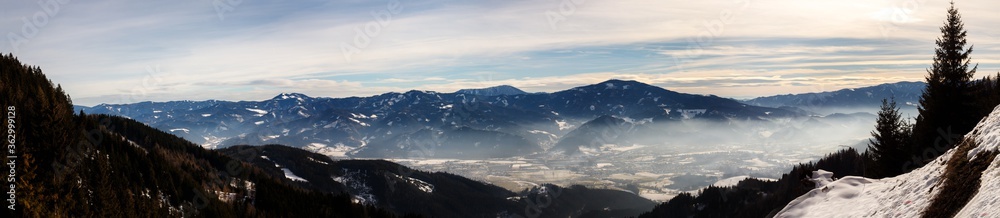clear blue panorama in the austrian alps with clouds and fog on a cold winter day