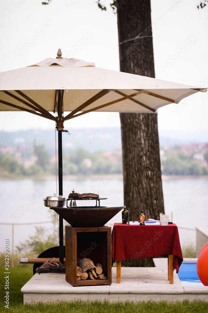 Barbecue and parasol in the yard by the river Photos | Adobe Stock