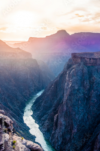 The Grand Canyon is seen in a majestic purple and blue sunset with multiple layers of rock cliffs leading down to the Colorado River below. Grand Canyon National Park, Arizona, USA