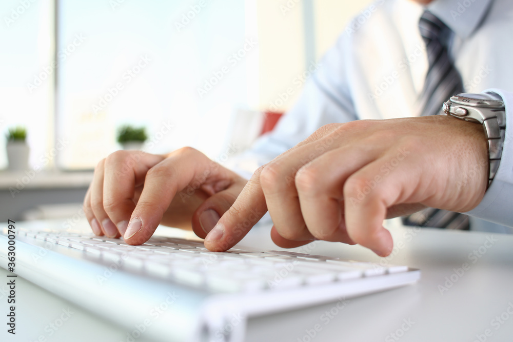 Close up of male company employee working alone while typing on keyboard with window on the background Close up of male company employee working alone while typing on keyboard with window on the background