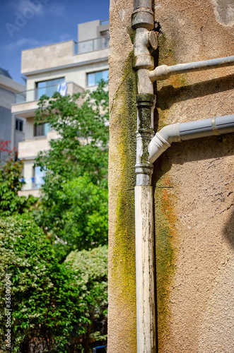 An old sewer pipe has been leaking for a long time on a wall of a residential house. 
