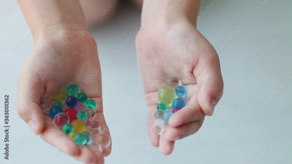 Children is hands scatter oreez on the floor. Decoration water balls hydrogel - orbeez.
