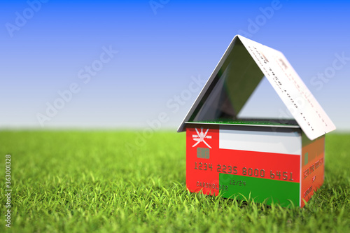 Flag of Oman on bank card house in the grass. Mortgage related 3D rendering photo