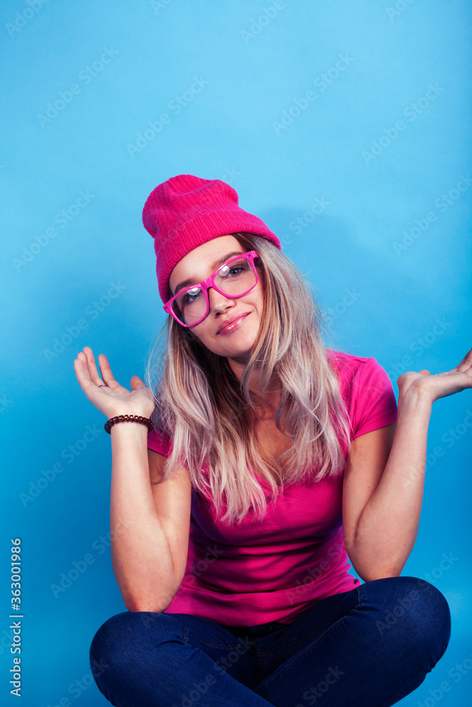 young pretty teenage modern hipster girl posing emotional happy on blue background, wearing pink hat and glasses, lifestyle people concept young pretty teenage modern hipster girl posing emotional happy on blue background, wearing pink hat and glasses, lifestyle people concept