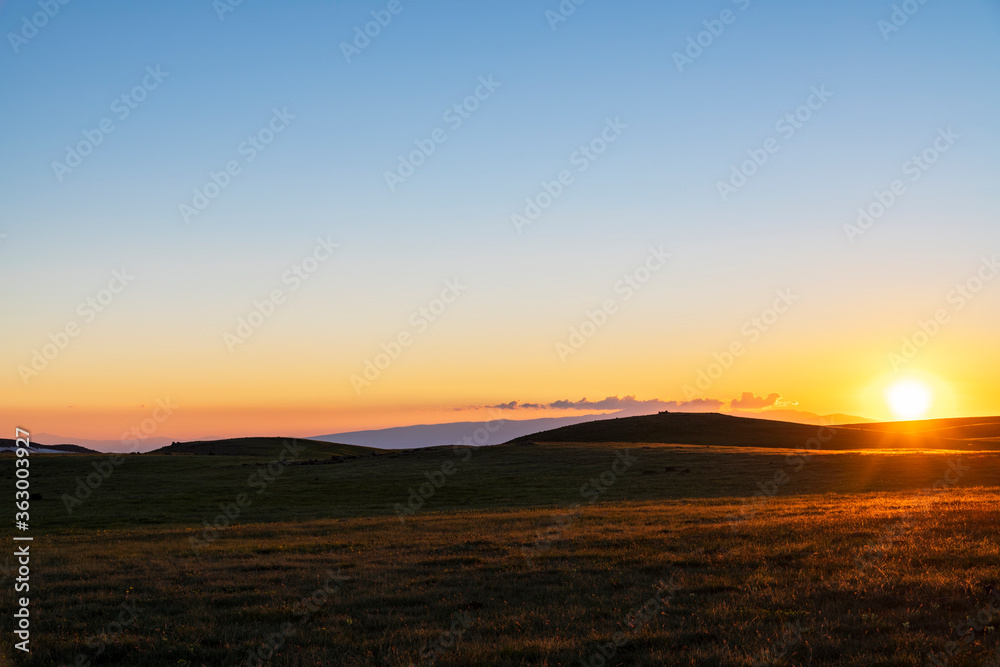 Beautiful sunset landscape. The green field and mountains illuminates the sun rays. Beautiful sunset landscape. The green field and mountains illuminates the sun rays.
