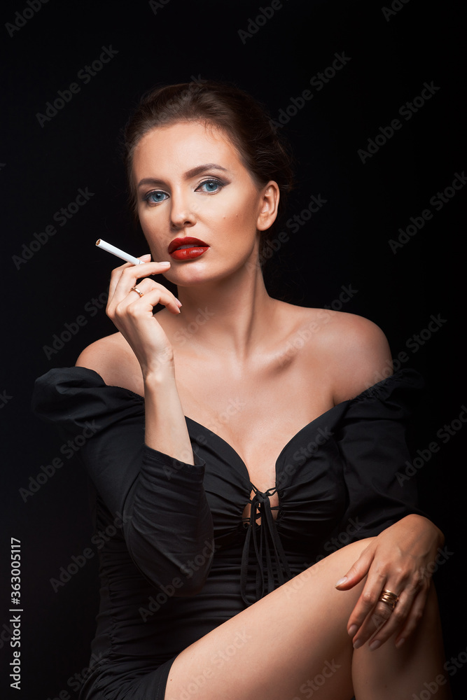 beautiful girl on a dark background in a dark dress looks into the frame with a cigarette in her hands and a hairdresser male hands beautiful girl on a dark background in a dark dress looks into the frame with a cigarette in her hands and a hairdresser male hands