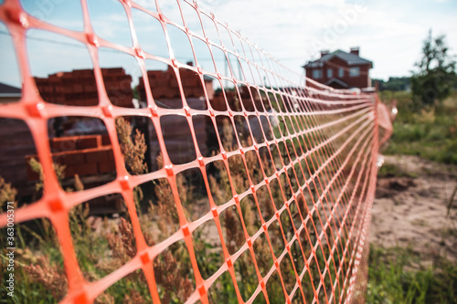 Construction site with bricks, fenced with mesh. Housing construction concept.
