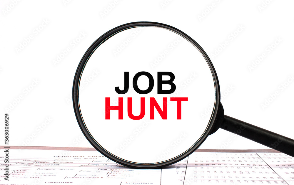 Magnifying glass with text Job Hunt on financial tables Magnifying glass with text Job Hunt on financial tables