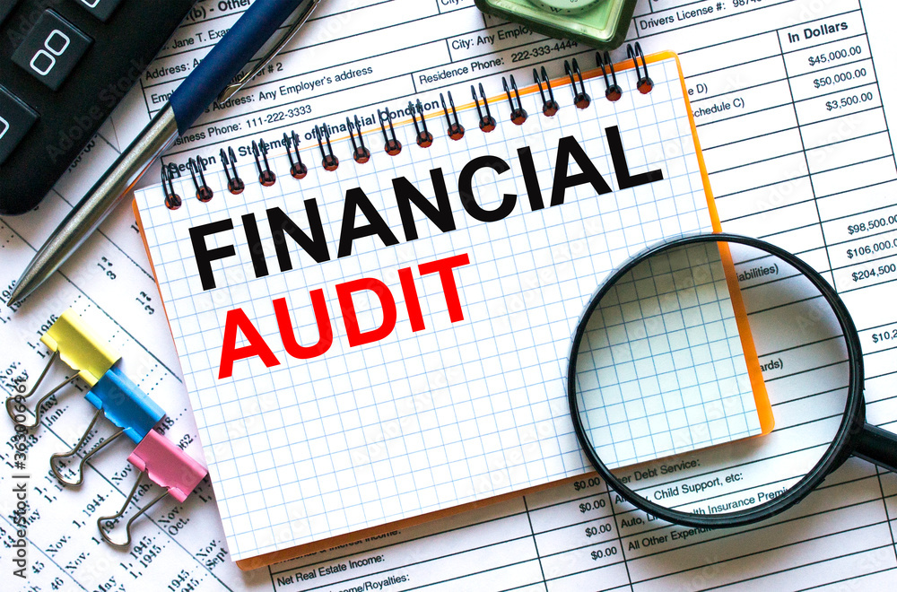 Obraz premium Text Financial Audit on notepad with calculator, clips, pen on financial report