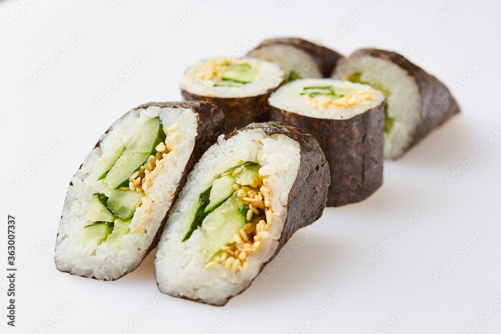 Vegetarian sushi rolls with cucumber and sesame seeds on a white background Vegetarian sushi rolls with cucumber and sesame seeds on a white background