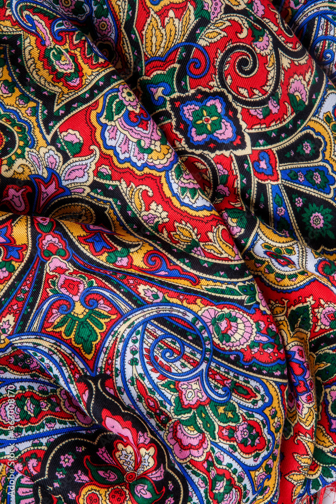 top view closeup on crumpled red cotton scarf with bright paisley floral ornament top view closeup on crumpled red cotton scarf with bright paisley floral ornament