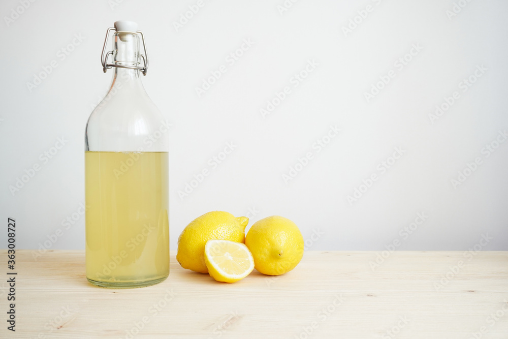 Lemonade in glass and bottle on wooden table. Lemonade or mojito cocktail with lemon and mint, cold refreshing drink or beverage with ice. Copy space for your text