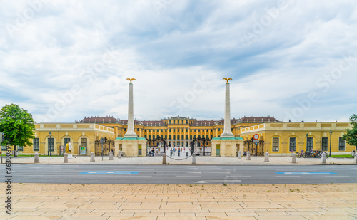 Vienna, Austria - june 25th 2020 - Exterior of the front of Schloss Schonbrunn seen from outside the gates during Corona time on a sunny day with some tourists visiting the palace photo