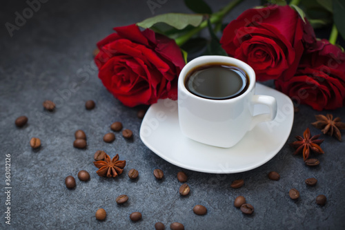White cup of coffee and red roses, flowers on a gray background