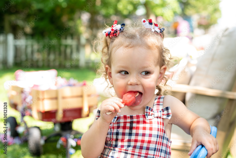 Cute toddler girl eating a red frozen fruit pop on Fourth of July Stock Photo Adobe Stock