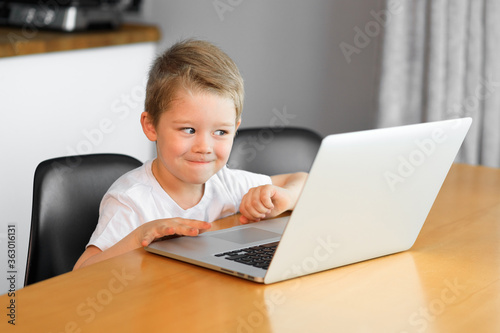 A little boy watches an educational video on a new laptop.