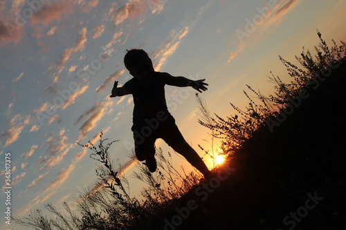   Boy runs on sunset background