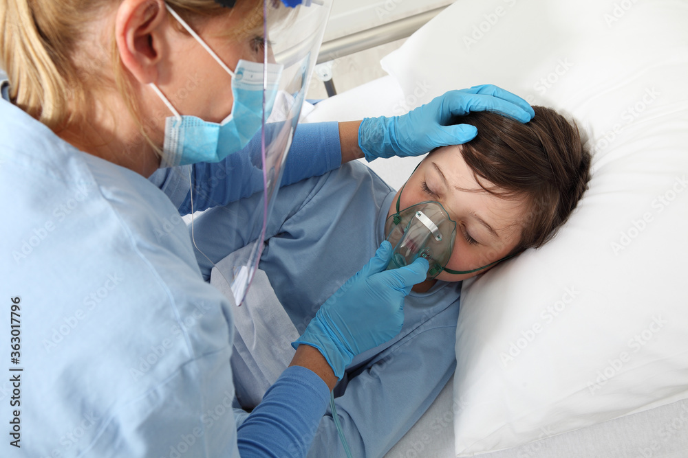 nurse puts oxygen mask on patient child in hospital bed, wearing protective visor mask, corona virus covid 19 protection concept, nurse puts oxygen mask on patient child in hospital bed, wearing protective visor mask, corona virus covid 19 protection concept,