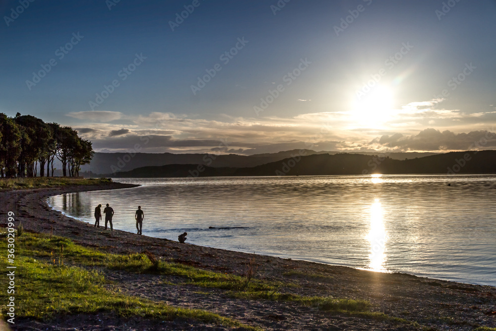 Family and dog by a loch at sunset
