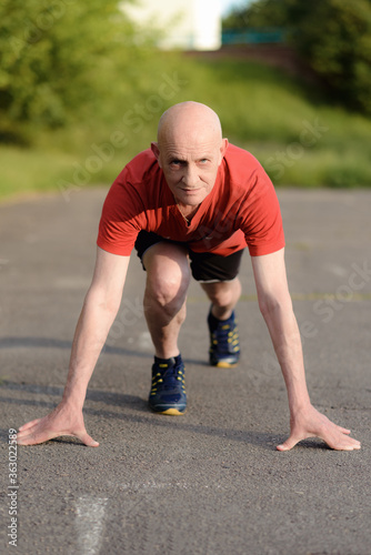 Senior man in position ready to run. Determined man ready for a sprint. Exercise Start Up Concept. © Ivan Kozachenko