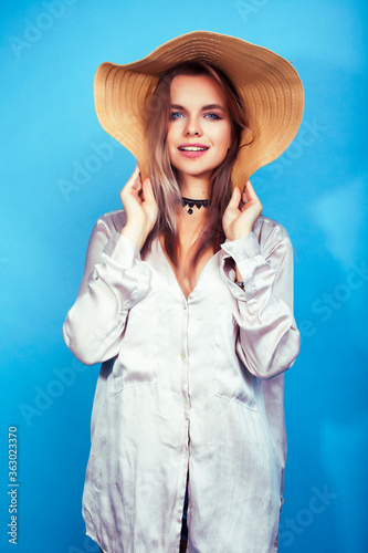 young pretty girl in big hat posing happy smiling on blue background, lifestyle people on summer vacation concept