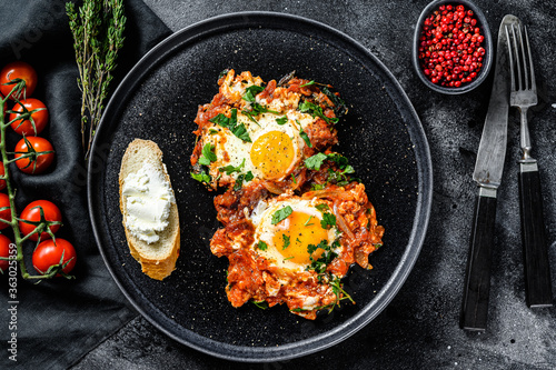 Shakshuka, Scrambled eggs with tomatoes and vegetables. Breakfast in the plate. Black background. Top view