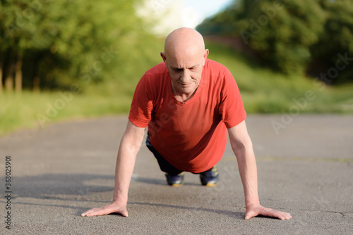 Senior sportsman doing push-ups in the park. High quality photo