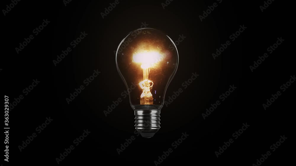 Tungsten light bulb isolated on black background. Glass and metal base. Lights up brightly with a blink and fades out. Loop video in 4K resolution