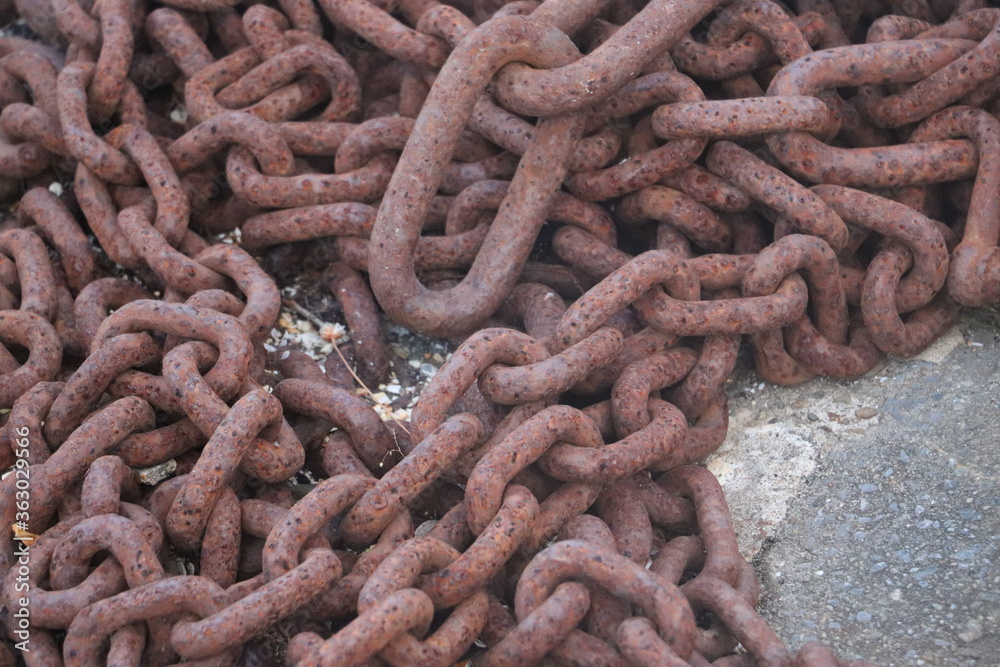 Rusty chain lying on the dockside with water in background Rusty chain lying on the dockside with water in background