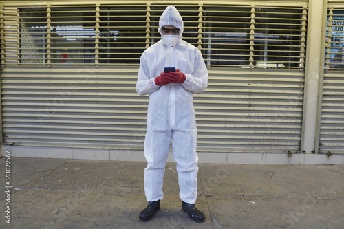 Front view shot of a person looking at a smartphone, wearing protective clothing