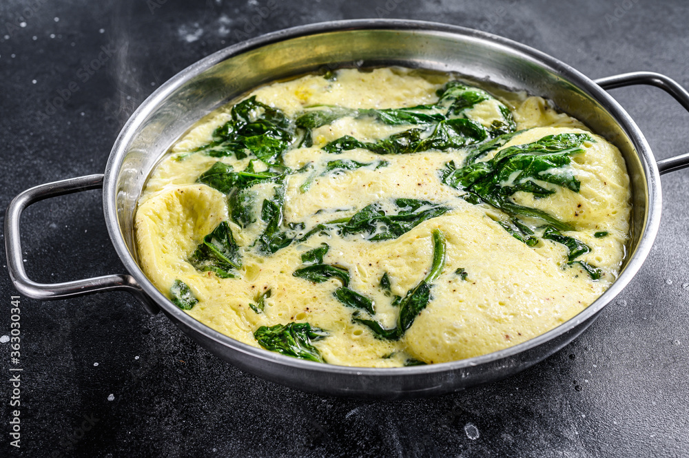 scrambled eggs with spinach and Parmesan cheese. Black background. Top view