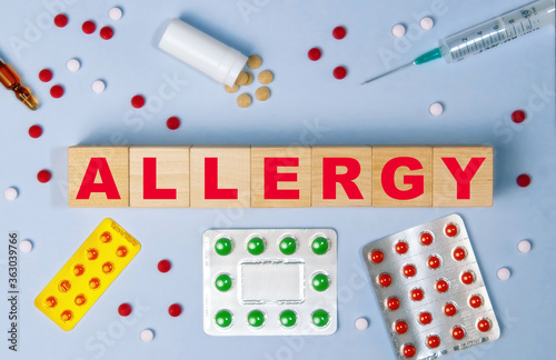 The word allergy on wooden cubes on the background of pills, syringe and ampoule. photo