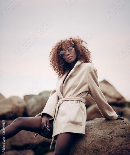 Fashion Girl Sitting on rock with sunglasses