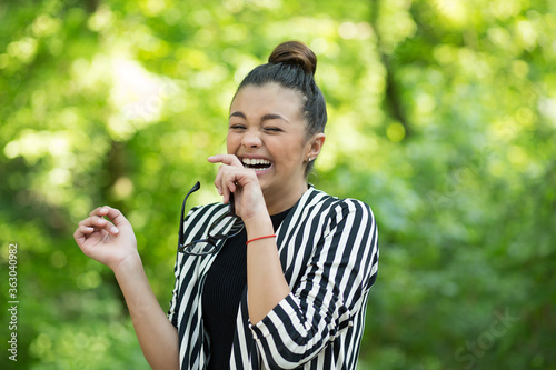 woman holding eyeglasses laughing happily outside