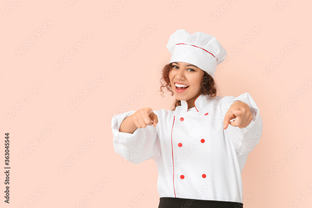 Female African-American chef pointing at viewer on color background Female African-American chef pointing at viewer on color background