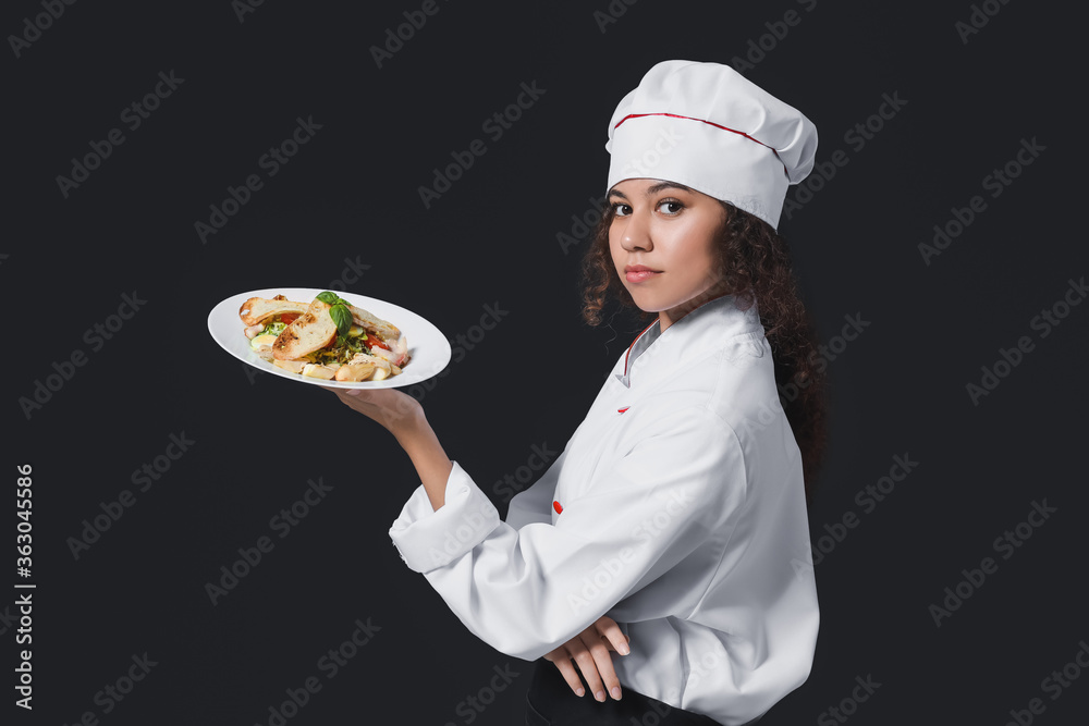 Female African-American chef with tasty dish on dark background Female African-American chef with tasty dish on dark background