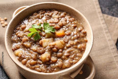 Pot of tasty lentils soup on table