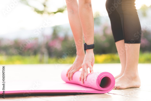 Close - up hands of young woman folding pink yoga or fitness mat after working out at the park. Healthy lifestyle, keep fit, Close up view photo