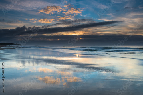 Sunrise Seascape with Clouds and Reflections on the Beach