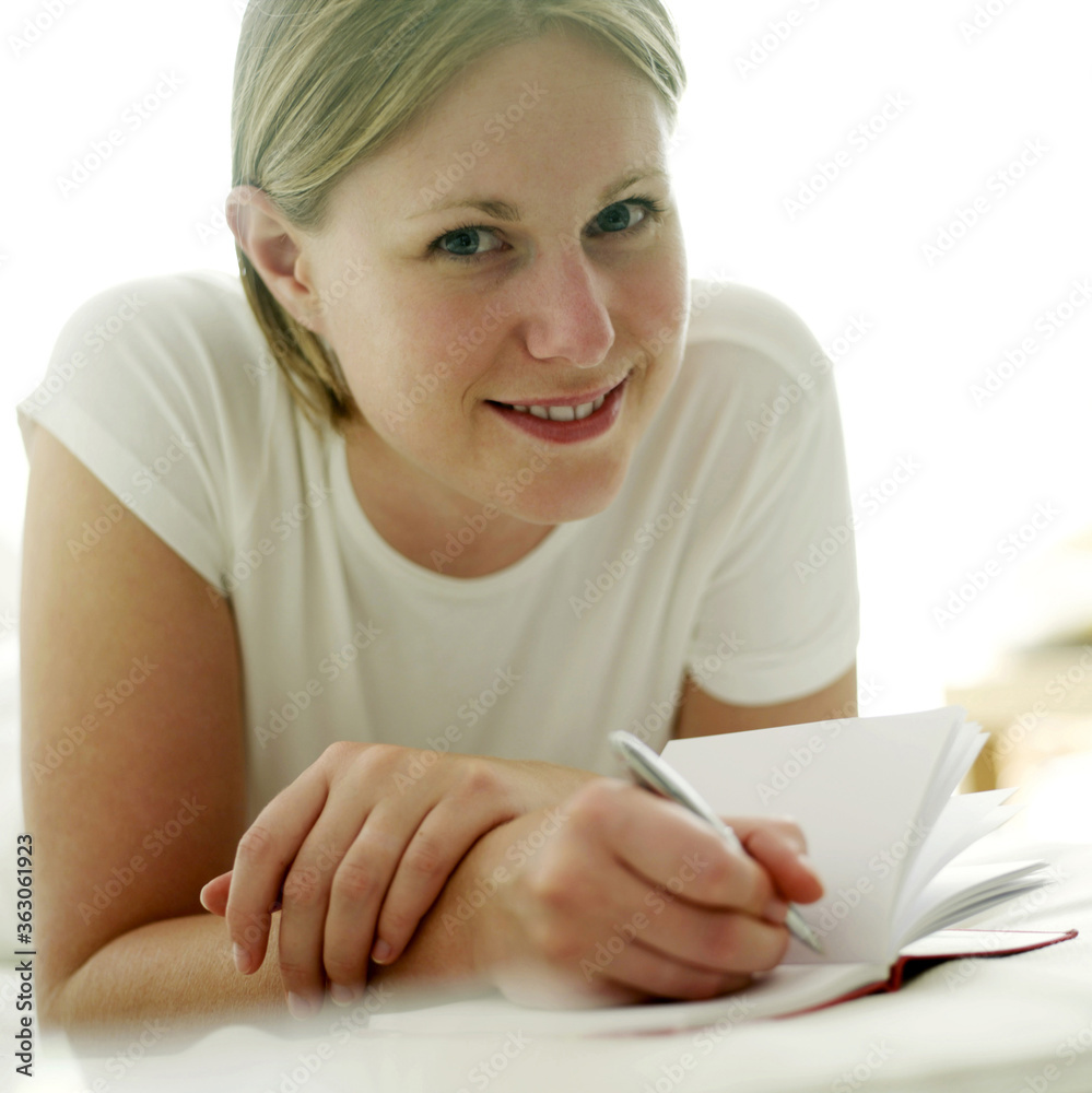 Woman lying forward on the bed writing journal Woman lying forward on the bed writing journal