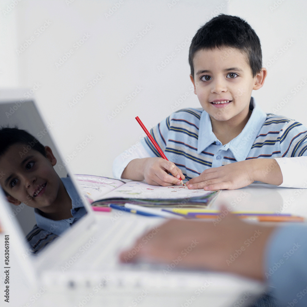 Boy doing homework while his father using laptop Boy doing homework while his father using laptop