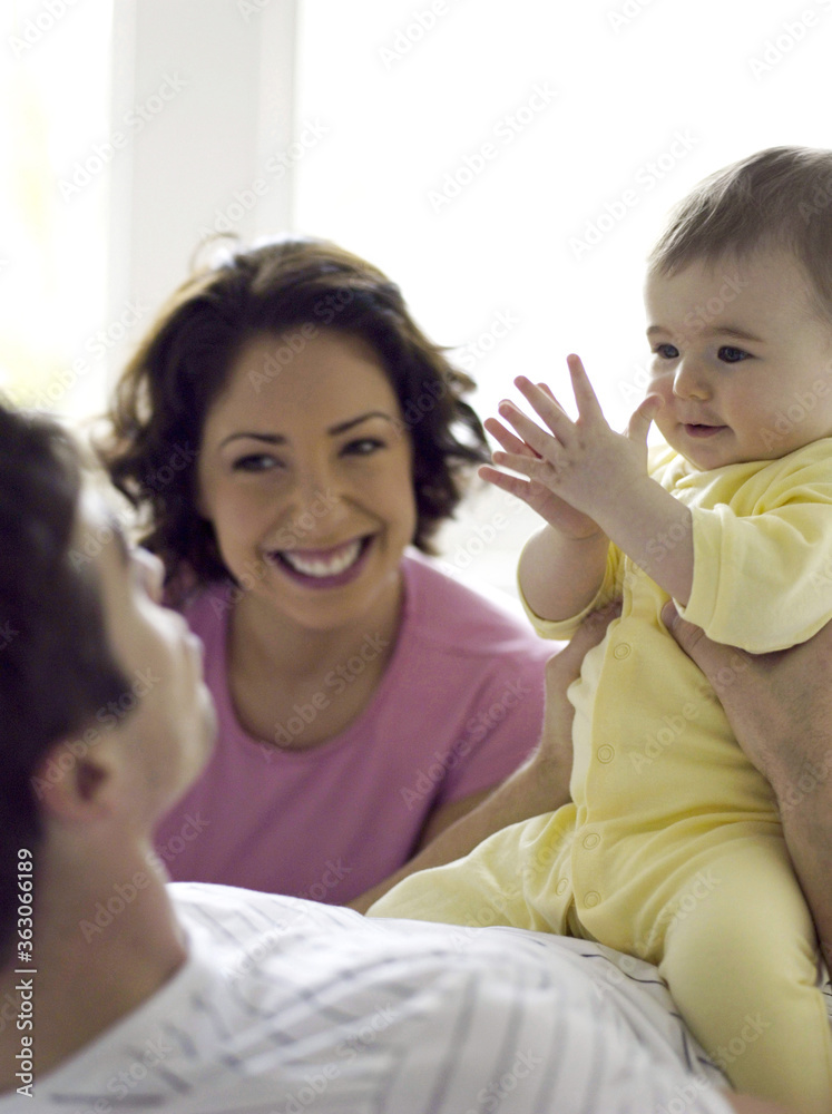 Mother watching father playing with baby girl Mother watching father playing with baby girl