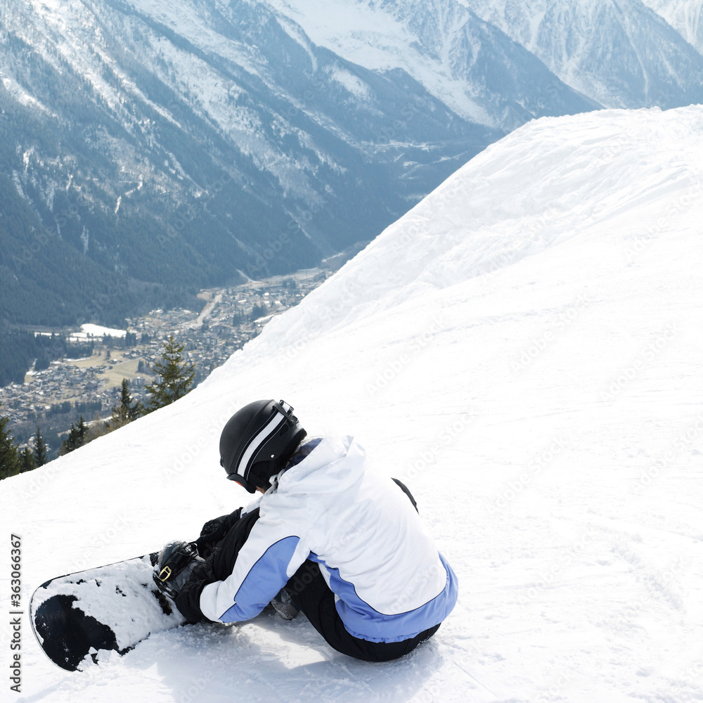 Obraz na plátně Female snowboarder strapping board onto feet