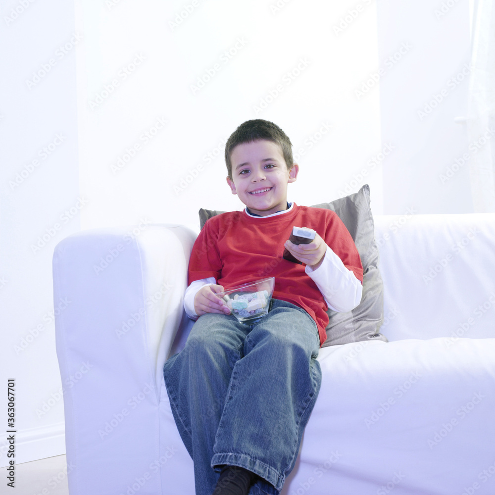 Boy holding a bowl of candies while watching television Boy holding a bowl of candies while watching television