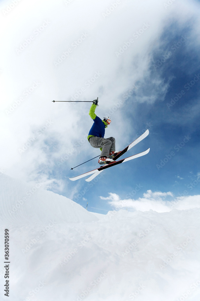 Man doing a mid air ski jump off a mountain