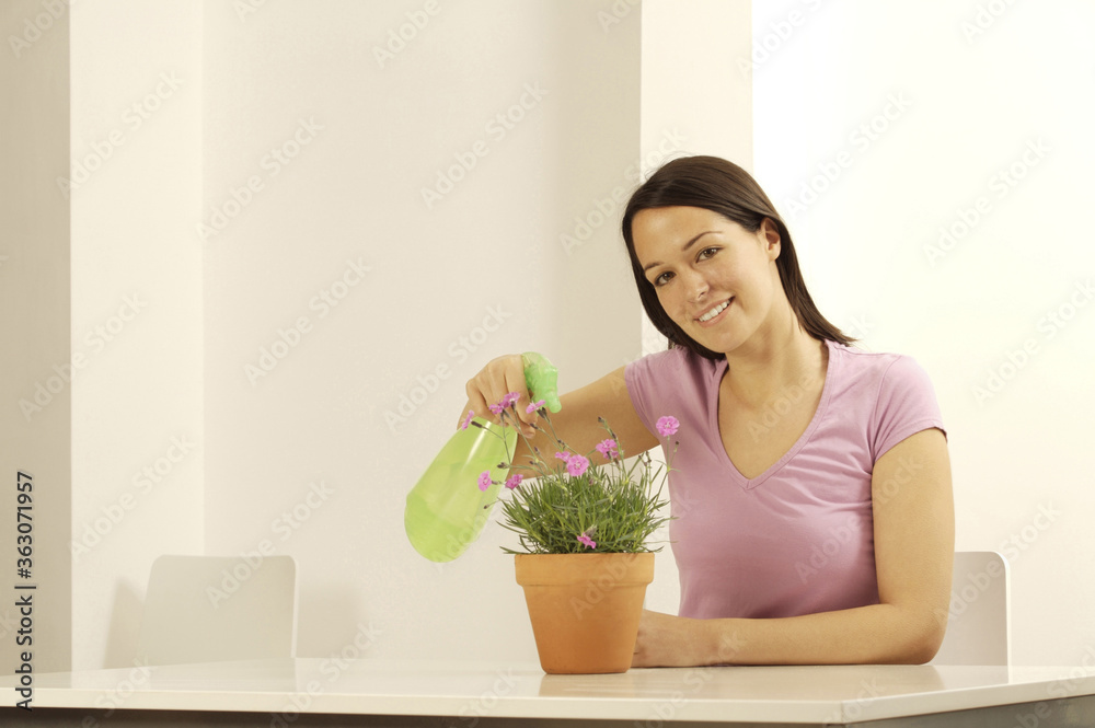 Woman spraying a potted flower