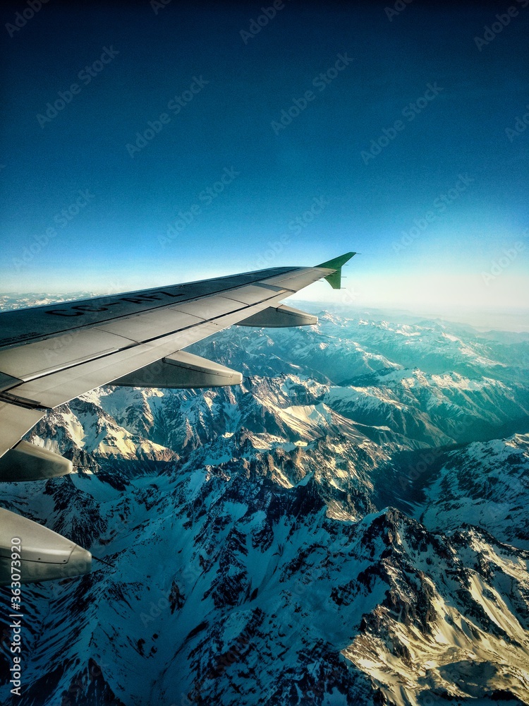 A view of the Andes mountains from an airplane, with snow and a sunlight