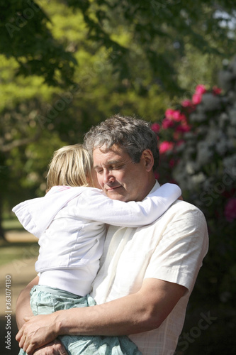 Senior man closing eyes while carrying girl