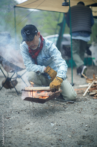 キャンプで薪を焚べる男性