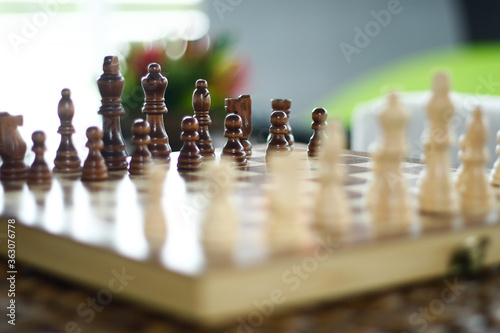 Tabuleiro de xadrez, com peças em madeira clara e escura.